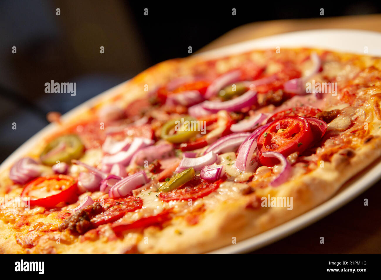 Fresca piccante crosta sottile pizza - jalepenos, manzo piccante, salsiccia per pizza, le cipolle rosse, chiudere il cibo la fotografia con gli elementi fuori fuoco Foto Stock