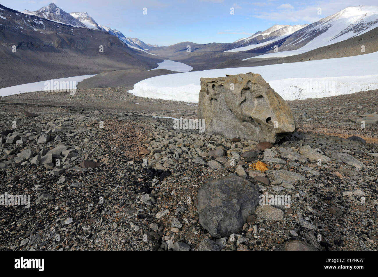 Taylor Valley, McMurdo aride vallate, Antartide guardando giù nella valle verso ricoperti di ghiaccio Lake Bonney con un grande ventifact in primo piano Foto Stock