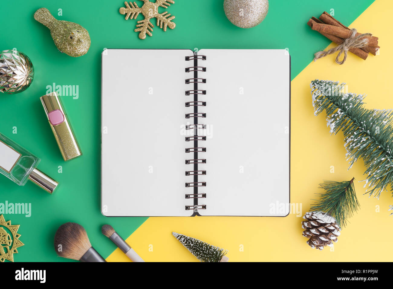 Creative laici piana di imbarcazioni e notebook vuoto mock up con ornamenti natale e costituiscono elementi di bellezza sul verde e sfondo giallo, vista superiore con Foto Stock