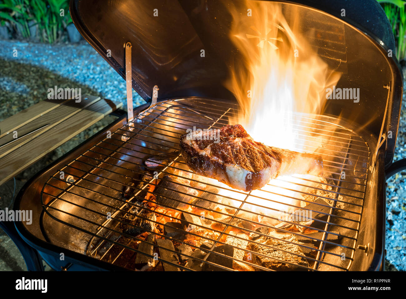 Grigliare un pezzo dello spessore secco di età con osso bistecca bistecca di manzo su una griglia a carbone con forte fuoco caldo Foto Stock