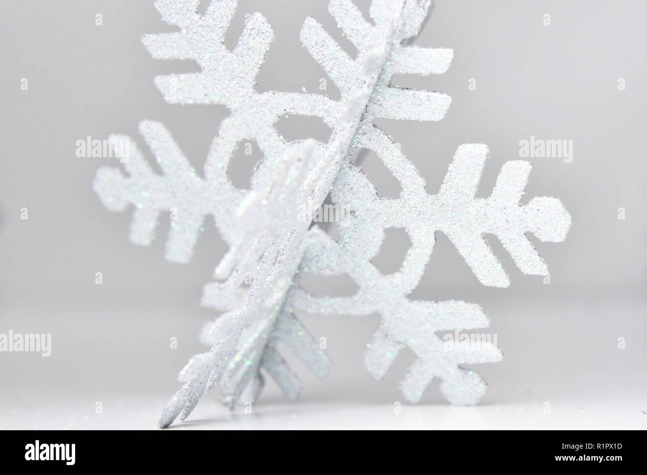 Scintillante bianco il simbolo del fiocco di neve in centro con sfondo bianco. Semplice Immagine invernale e il decor. Foto Stock