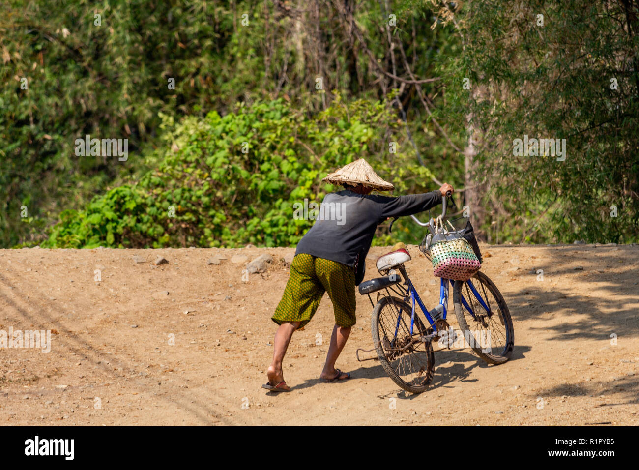 Don Det, Laos - Aprile 22, 2018: Locale uomo in possesso di una bicicletta in una remota zona rurale del sud Laos vicino al confine cambogiano Foto Stock