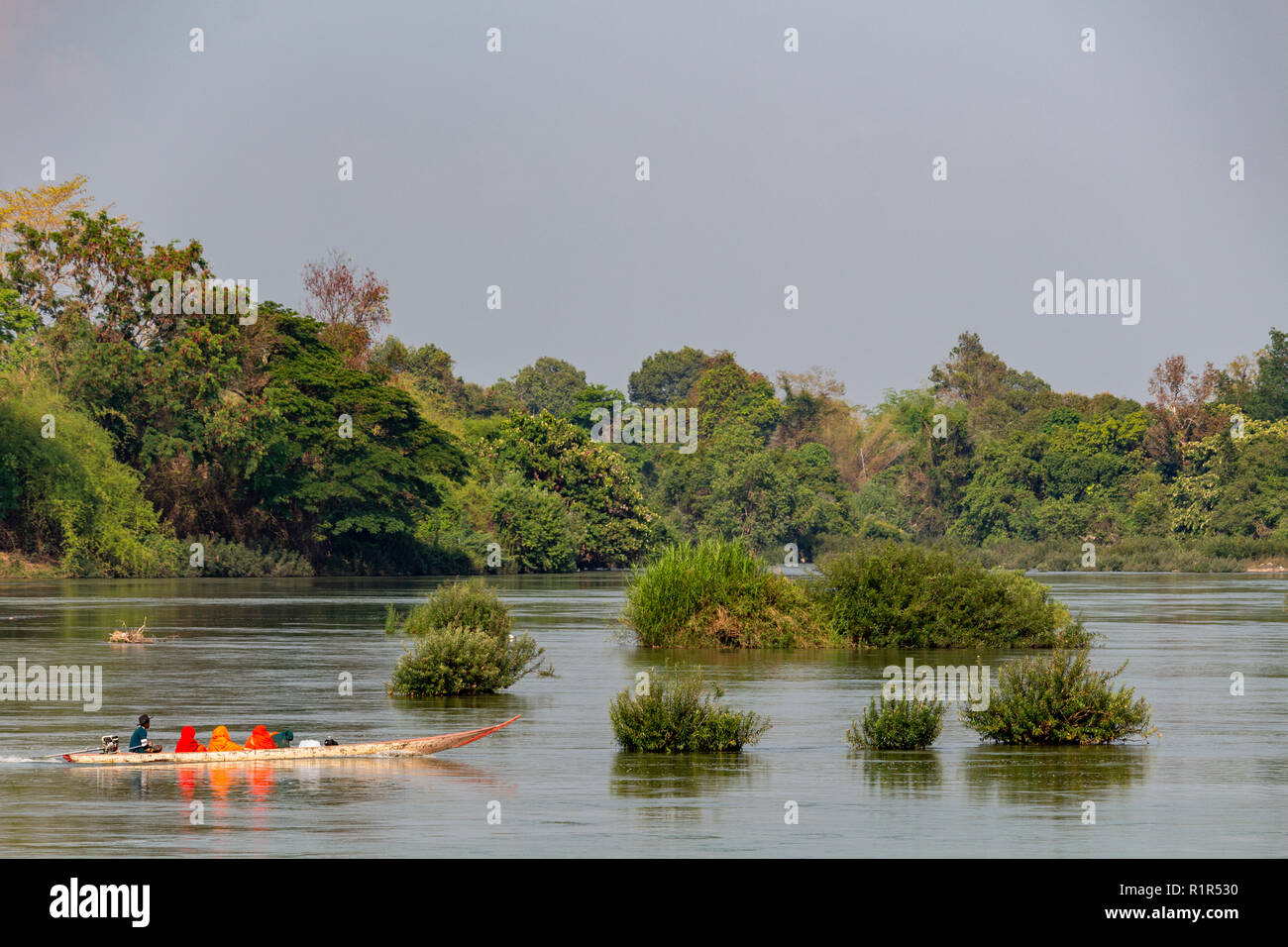 Don Det, Laos - Aprile 22, 2018: di legno longboat navigare il fiume Mekong circondato da foresta vicino al confine con la Cambogia Foto Stock