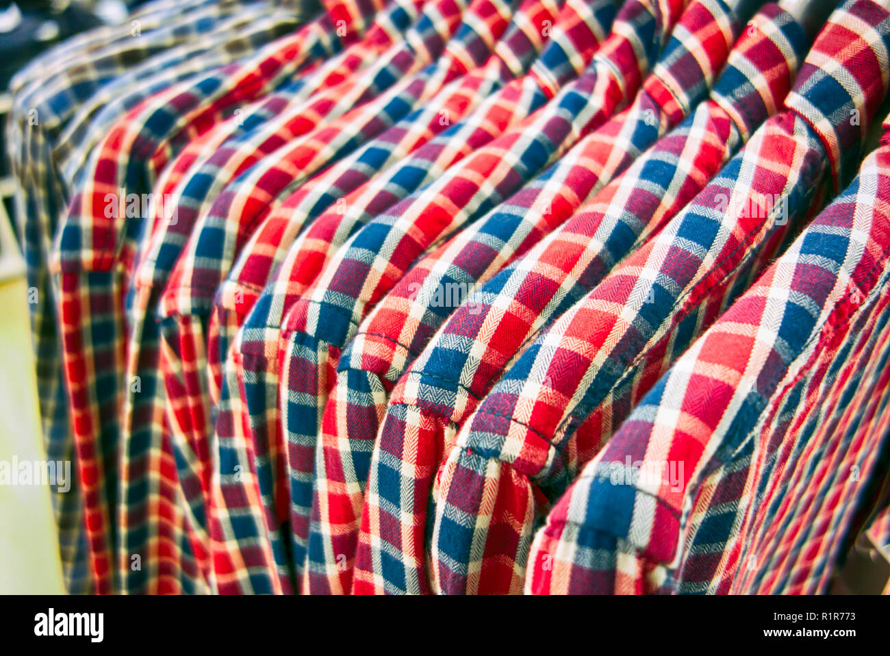 Una fila di plaid camicie appeso su appendiabiti in negozio. Close-up. Foto Stock