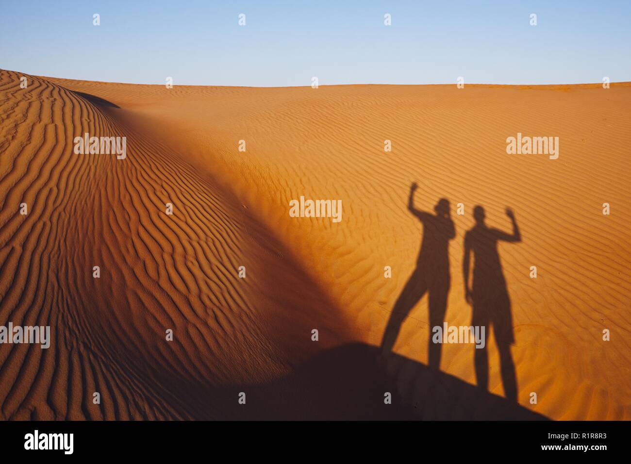 Le ombre dei due amici sventolare sul messaggio di saluto. Le dune di sabbia in Oman deserto. Foto Stock