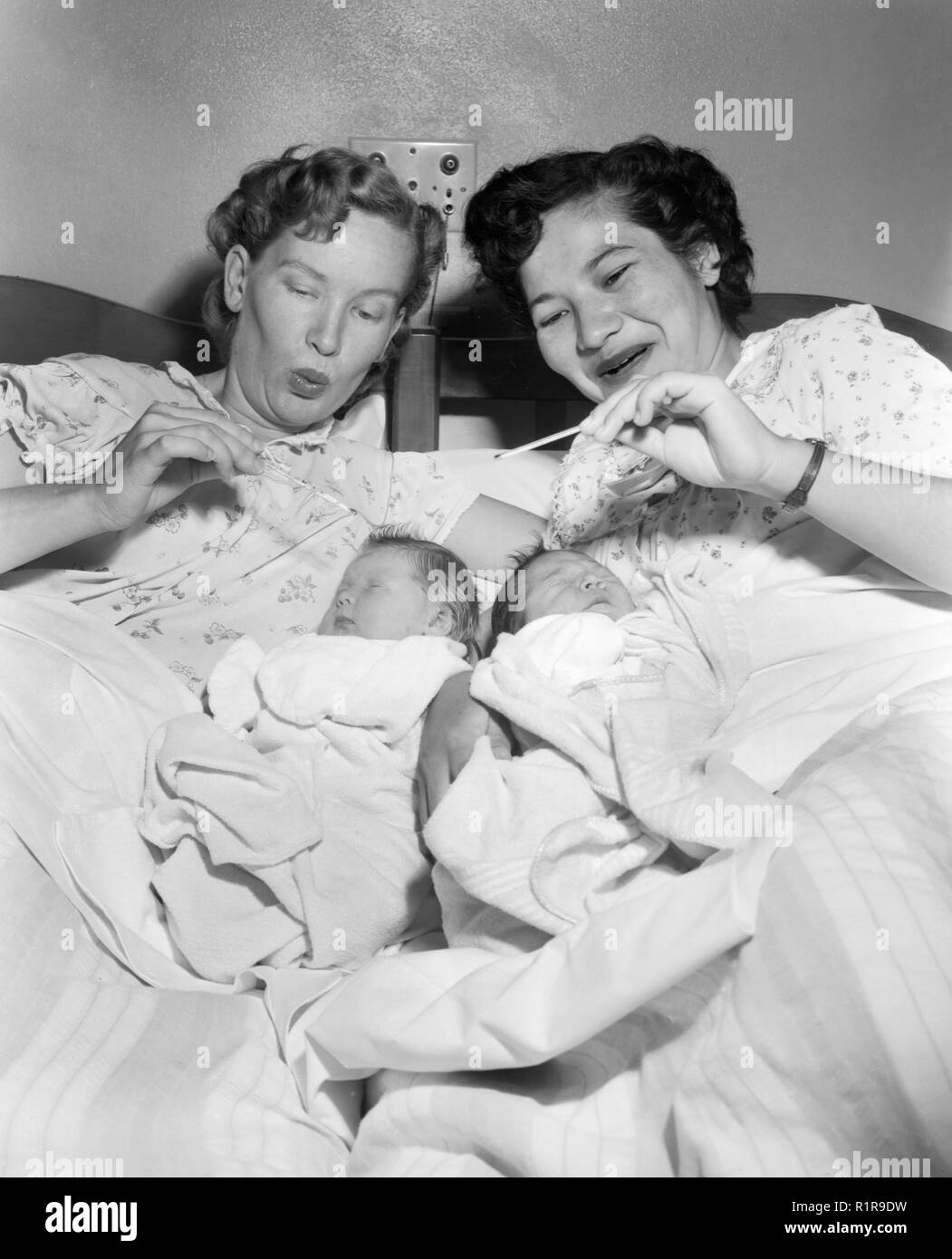 Due nuove mamme controllare la temperatura dei loro bambini, ca. 1960. Foto Stock