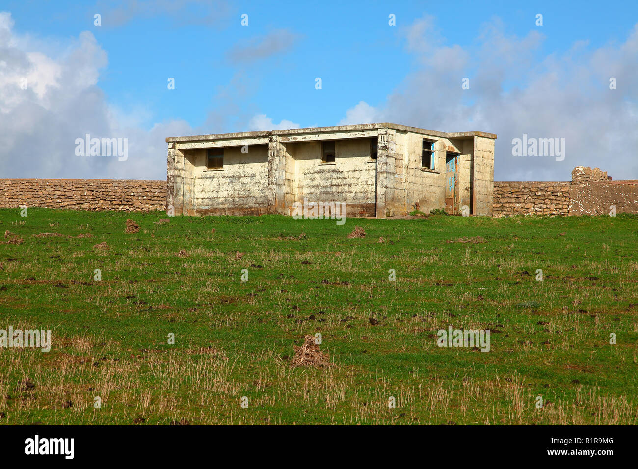 Un vecchio abbandonato wc pubblico blocco isolato in mezzo a un campo in alto sulla cima di un'immensa scogliera vicino Southerndown Foto Stock