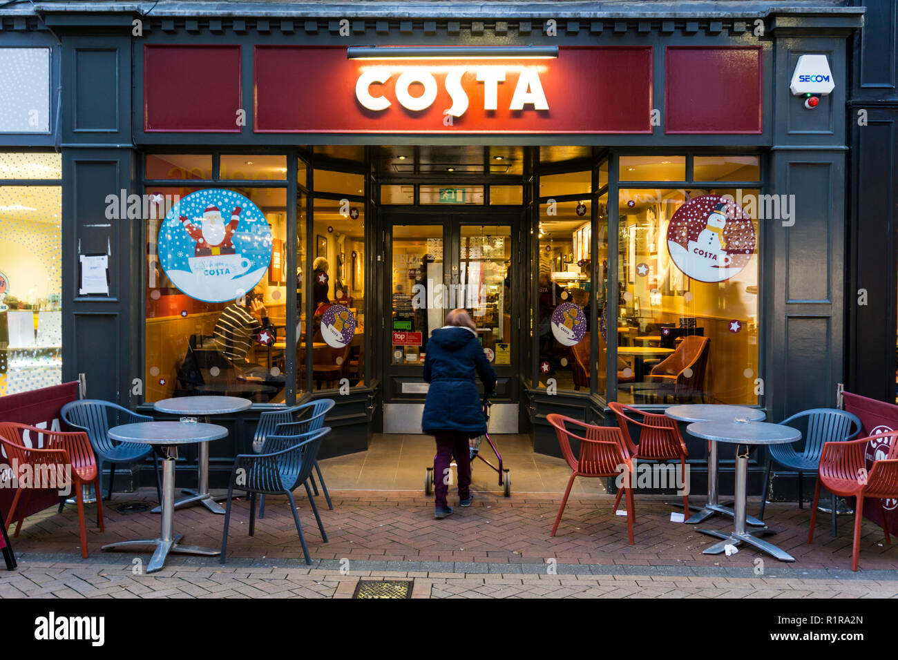 Una donna entra in un ramo di Costa Coffee in King's Lynn High Street al crepuscolo. Foto Stock