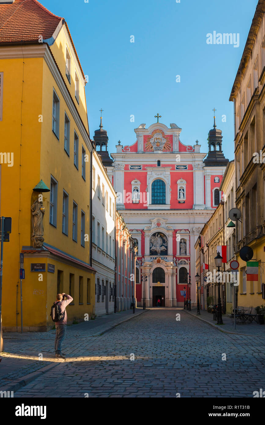 Fotografa un uomo, un fotografo di viaggio maschile solitario scatta una fotografia della facciata barocca della chiesa di San Stanislao, città vecchia di Poznan, Polonia. Foto Stock