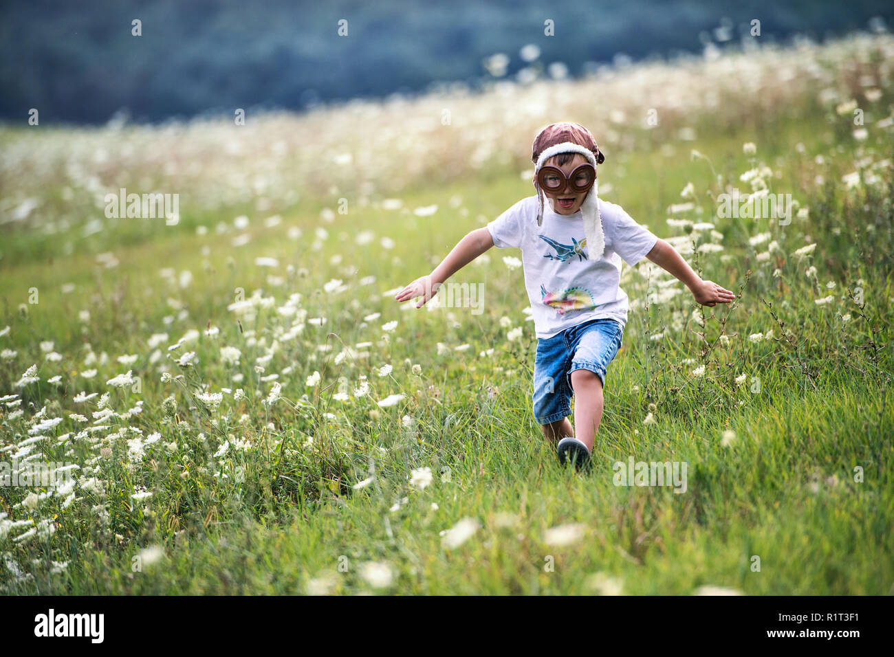 Un piccolo ragazzo con occhiali da pilota e hat in esecuzione in natura in un giorno di estate. Foto Stock