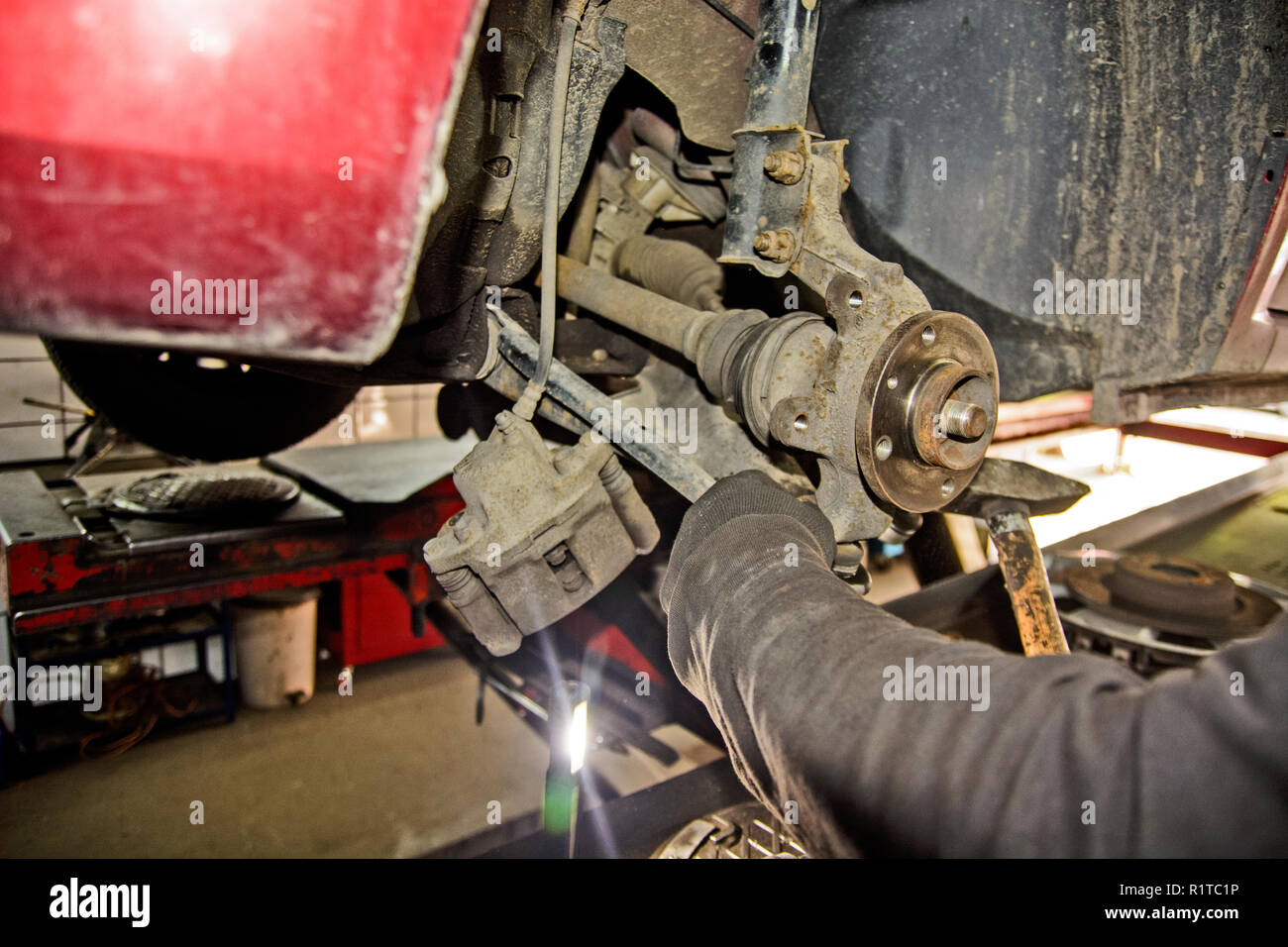 Il meccanico in officina sostituisce il cuscinetto sull'assale anteriore della macchina. Foto Stock