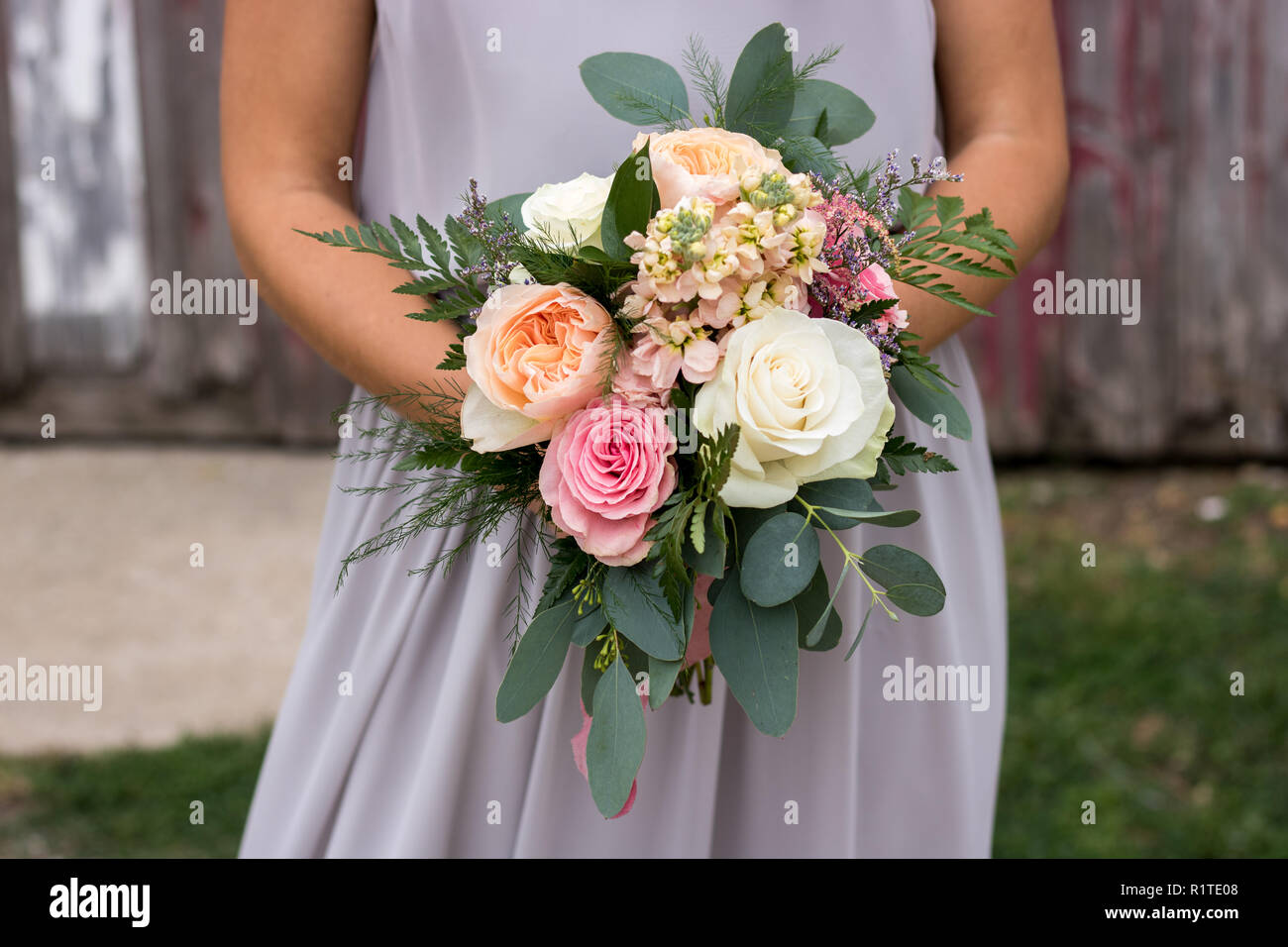 Damigella in viola tenendo un bellissimo mazzo di fiori. Foto Stock