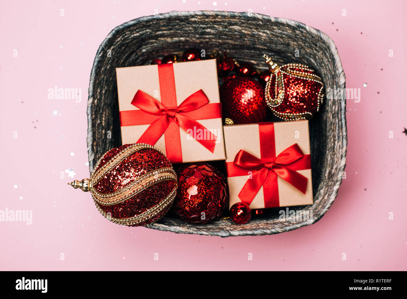 Scatola d'argento con presenta colore rosso e palle di Natale rosa su sfondo color pastello. Lay piatto. Anno nuovo concetto. Foto Stock