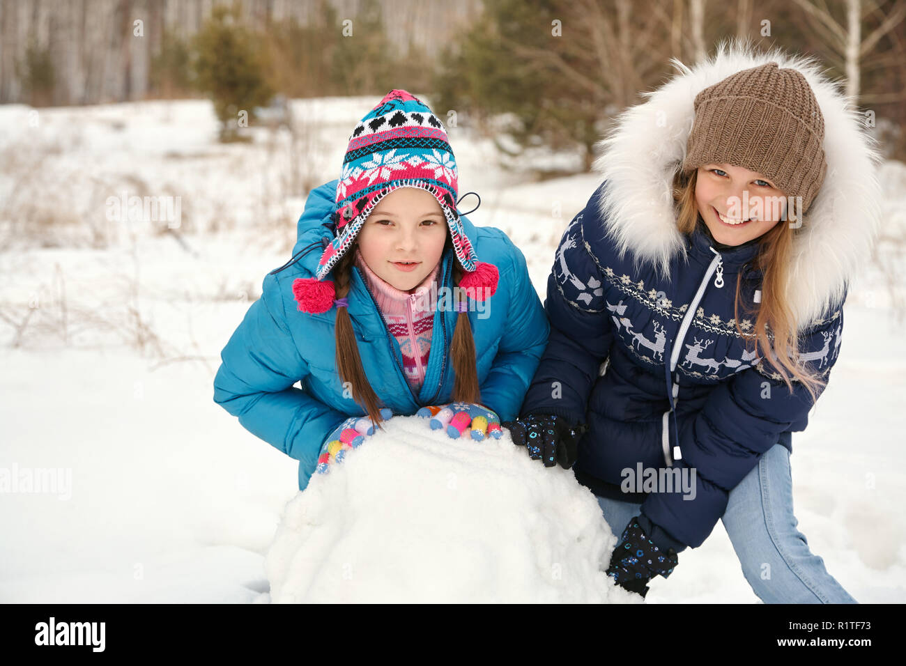 Due amiche costruire un pupazzo di neve. funny ragazze su una passeggiata in inverno all'aperto Foto Stock