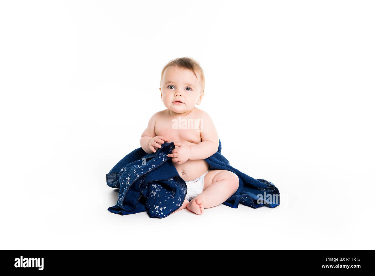 Il bambino sotto un asciugamano. Età di dieci mesi. Esso è isolato su sfondo bianco Foto Stock