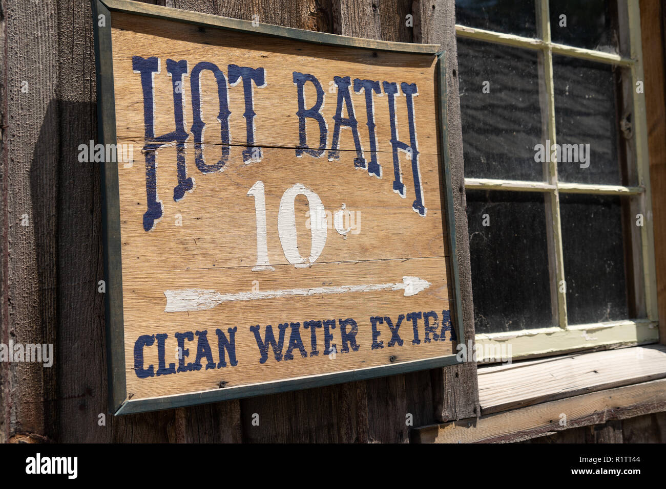 Segno divertenti per un bagno caldo acqua pulita Extra per dieci centesimi su un legno rustico edificio abbandonato Foto Stock