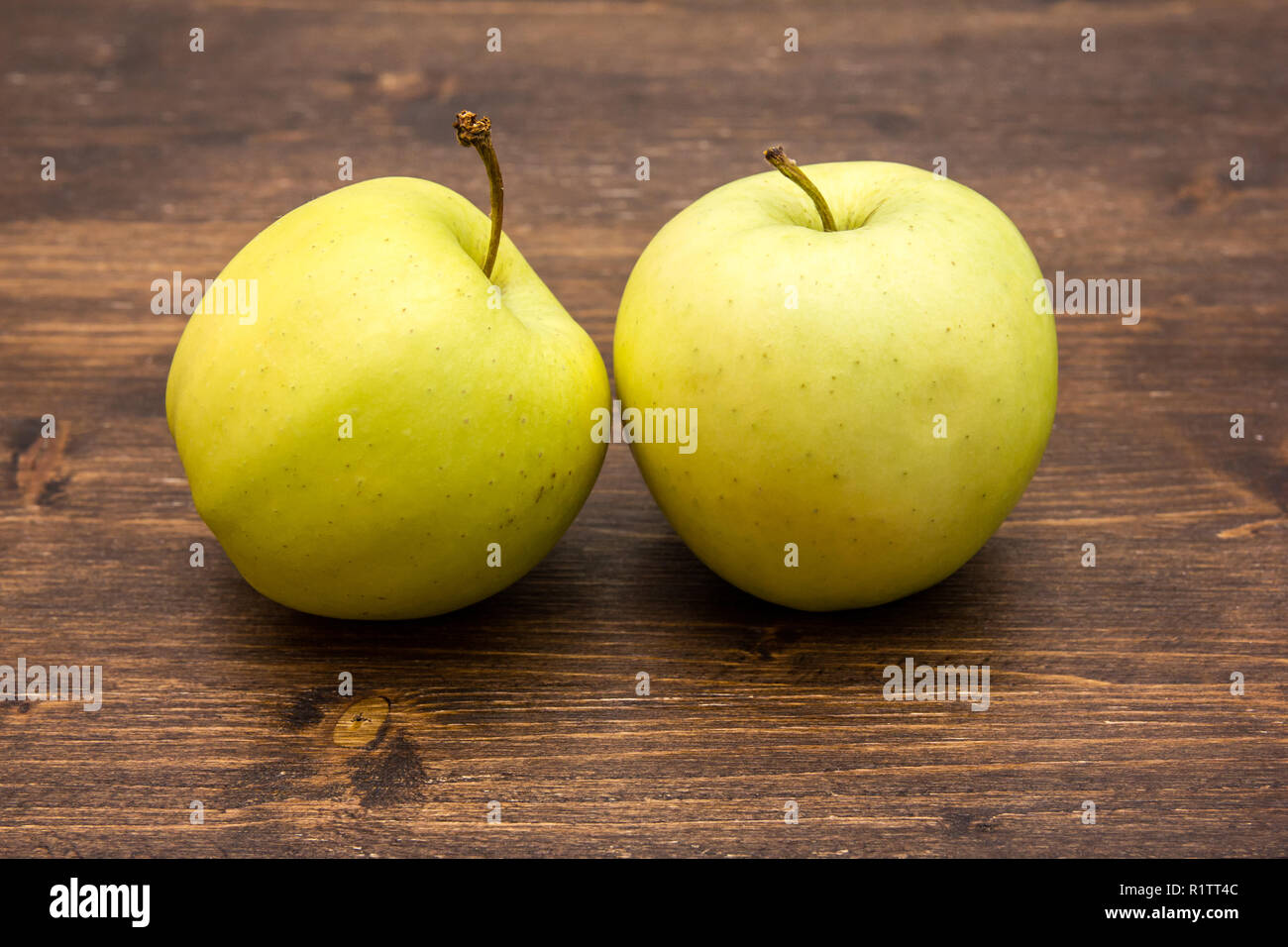 Due mele giallo su un tavolo di legno Foto Stock