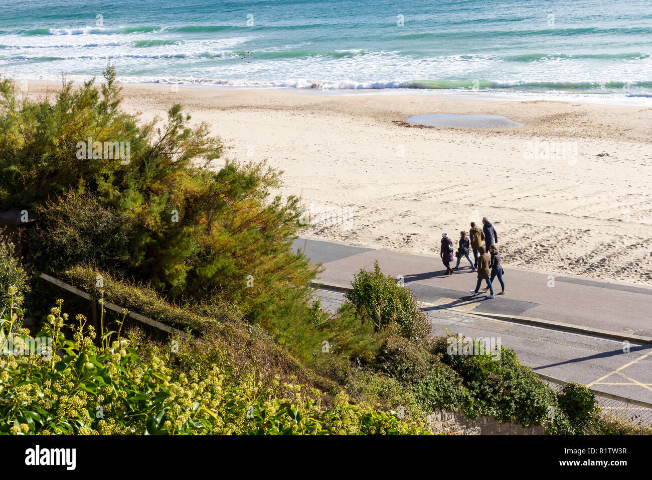 Un gruppo di persone per un autunno domenica pomeriggio passeggiata lungo il mare, Bournemouth Beach, REGNO UNITO Foto Stock