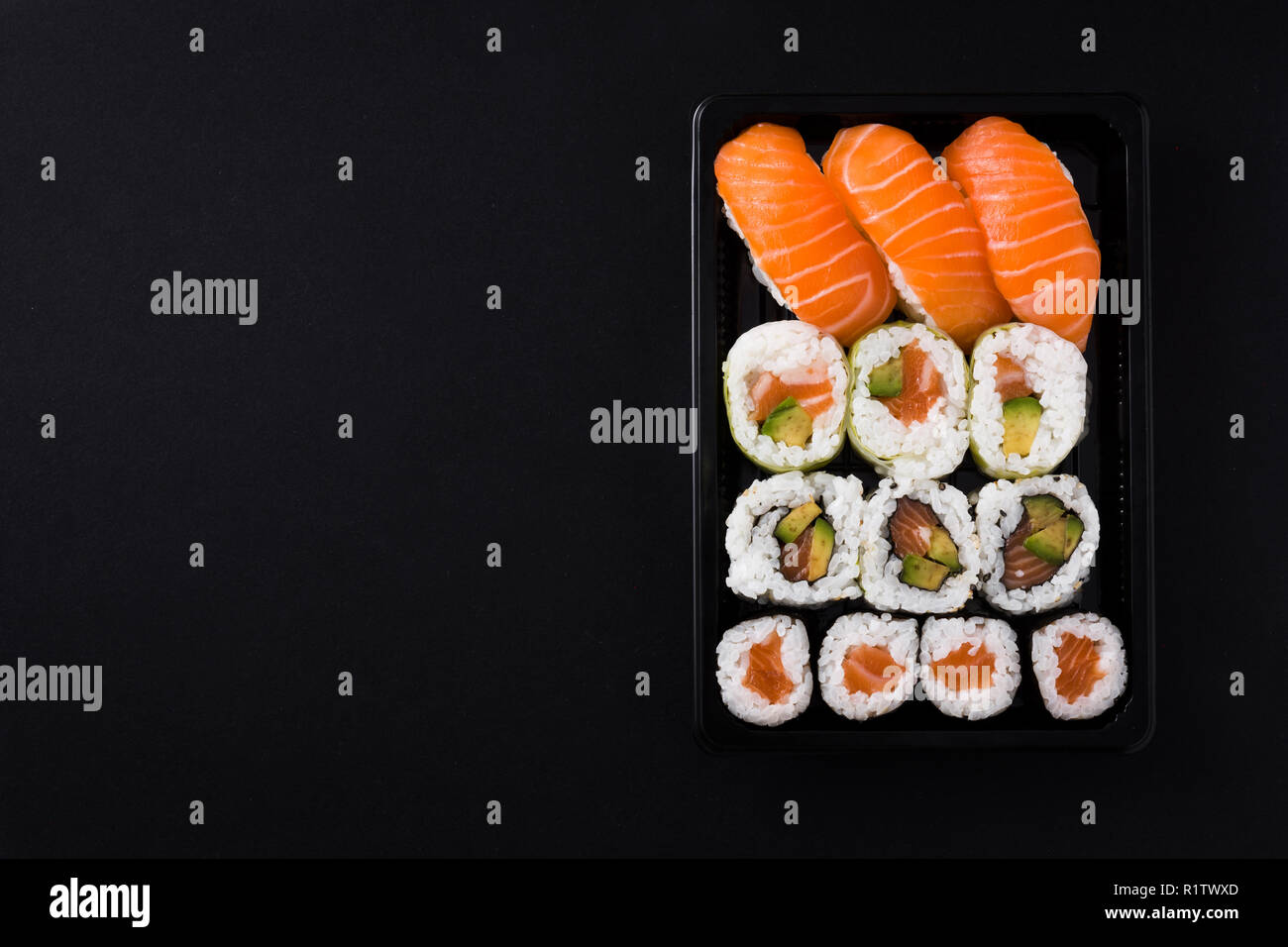 Il cibo giapponese: maki e nigiri sushi set su sfondo nero. Laici flat top-down composizione. Copyspace Foto Stock