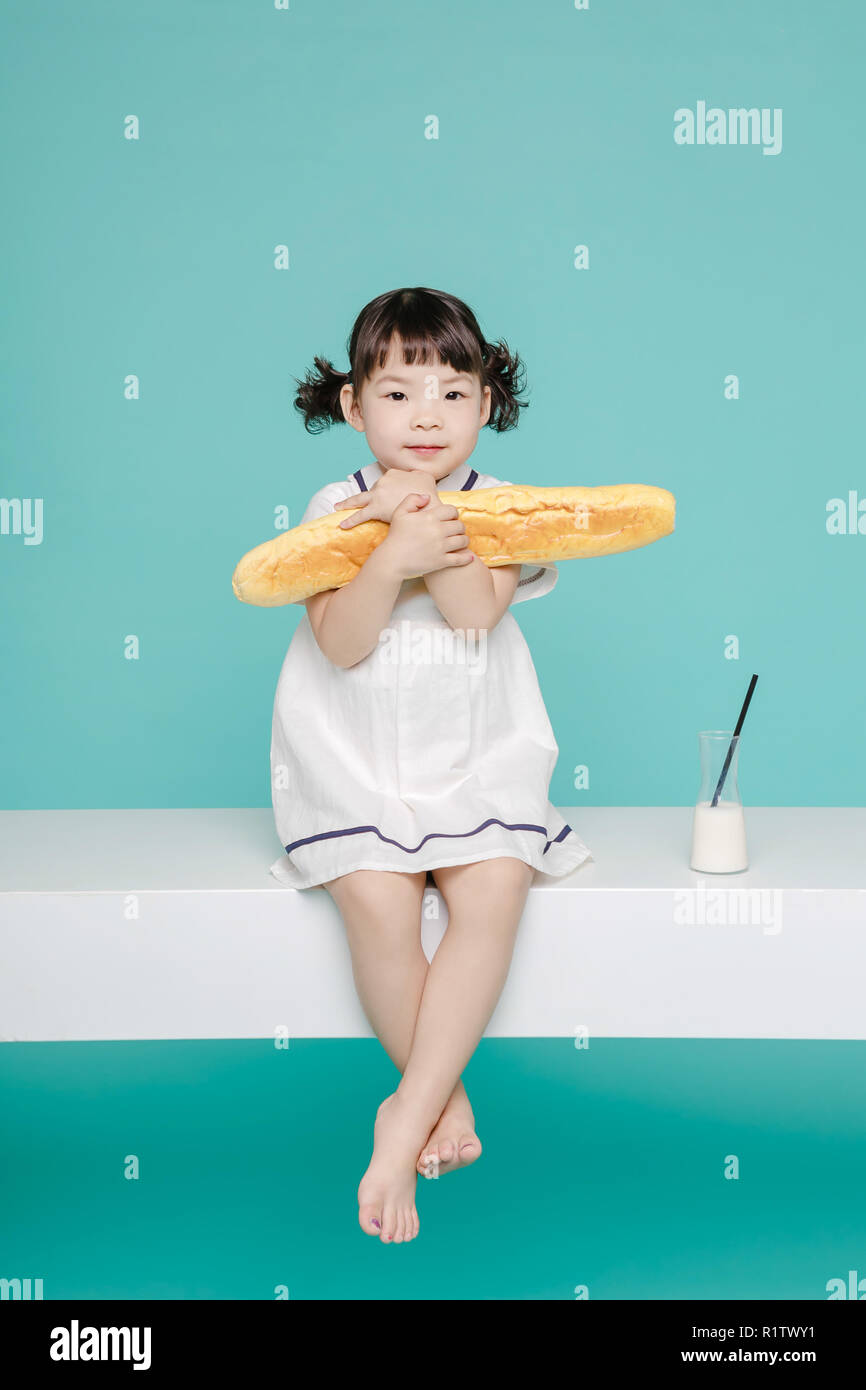 Poco bella ragazza asiatica di ridere ritratto con latte e pane, lifestyle sano e felice. Foto Stock