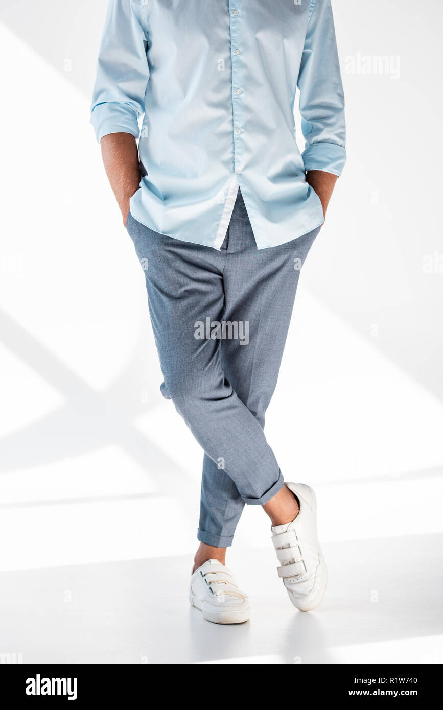 Ritagliato shot dell uomo in eleganti pantaloni e camicia e scarpe di bianco in piedi su bianco Foto Stock