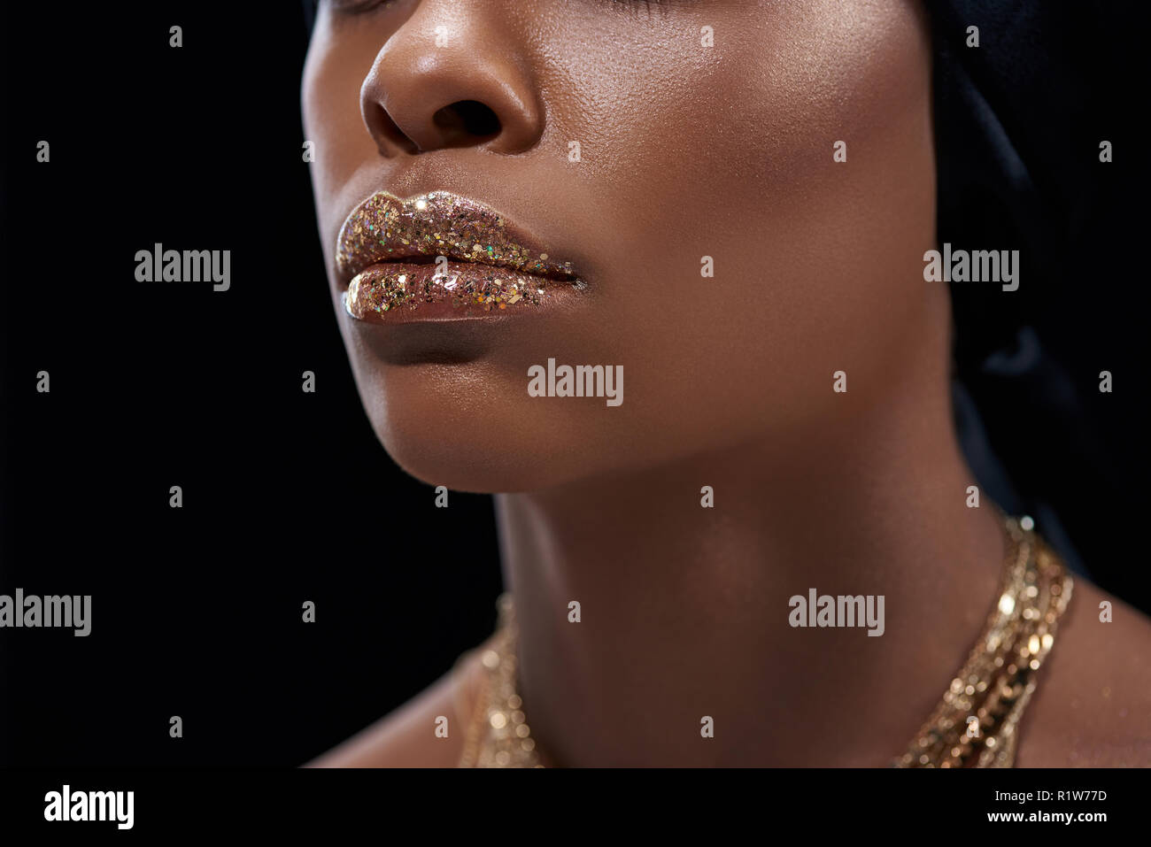 Ritagliato colpo di African American donna con spumante lip gloss isolato su nero Foto Stock