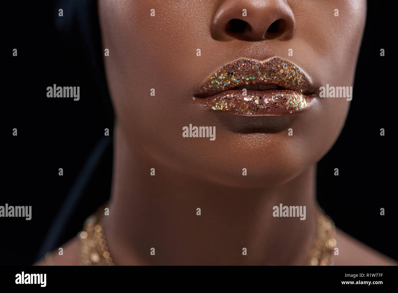 Ritagliato colpo di African American donna con spumante lip gloss isolato su nero Foto Stock