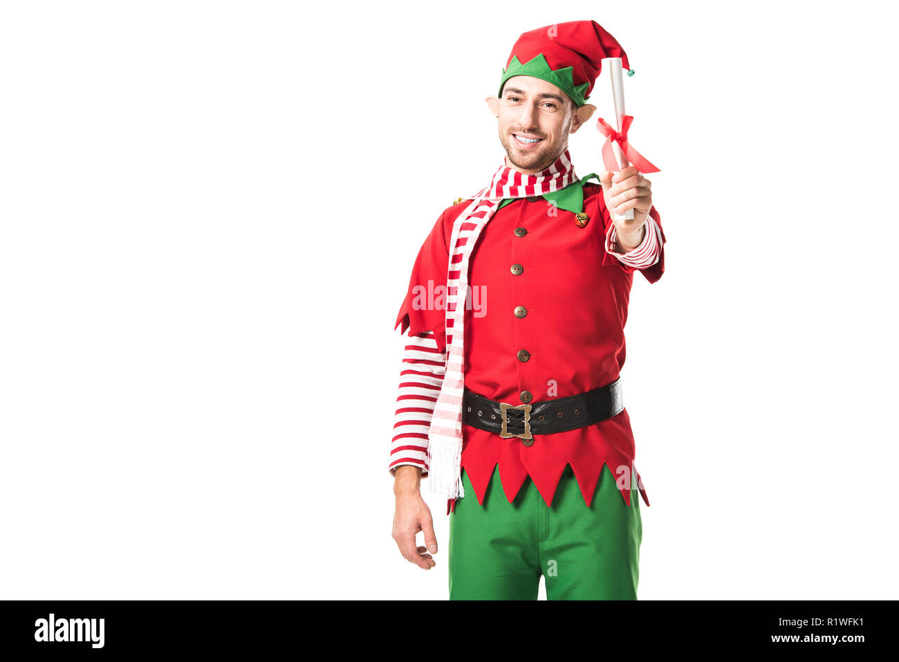 Uomo sorridente in elf natale costume holding wishlist roll e guardando la telecamera isolato su bianco Foto Stock