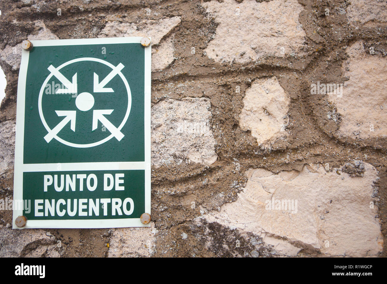 Punto di incontro segno attaccato al muro di pietra. Spanish languaje lettera Foto Stock
