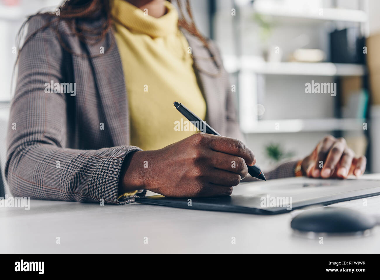 Sezione mediana di African American designer con tavoletta grafica alla scrivania in ufficio moderno Foto Stock