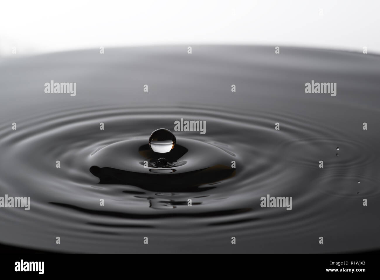 Acqua goccia caduta in acqua facendo a cerchi concentrici Foto Stock