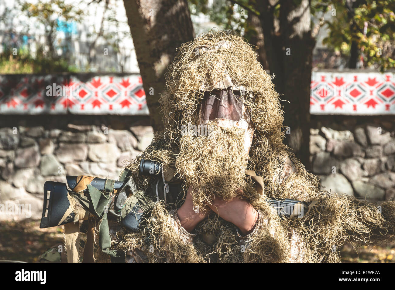 Mimetizzati mantiene sniper rifle . Soldato vestito in mimetica ghillie sulla natura. Foto Stock