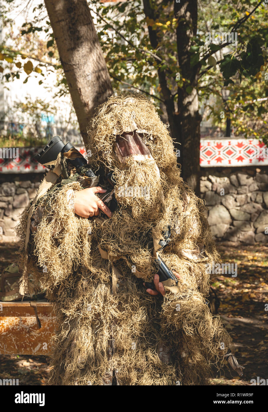 Mimetizzati mantiene sniper rifle . Soldato vestito in mimetica ghillie sulla natura. Foto Stock