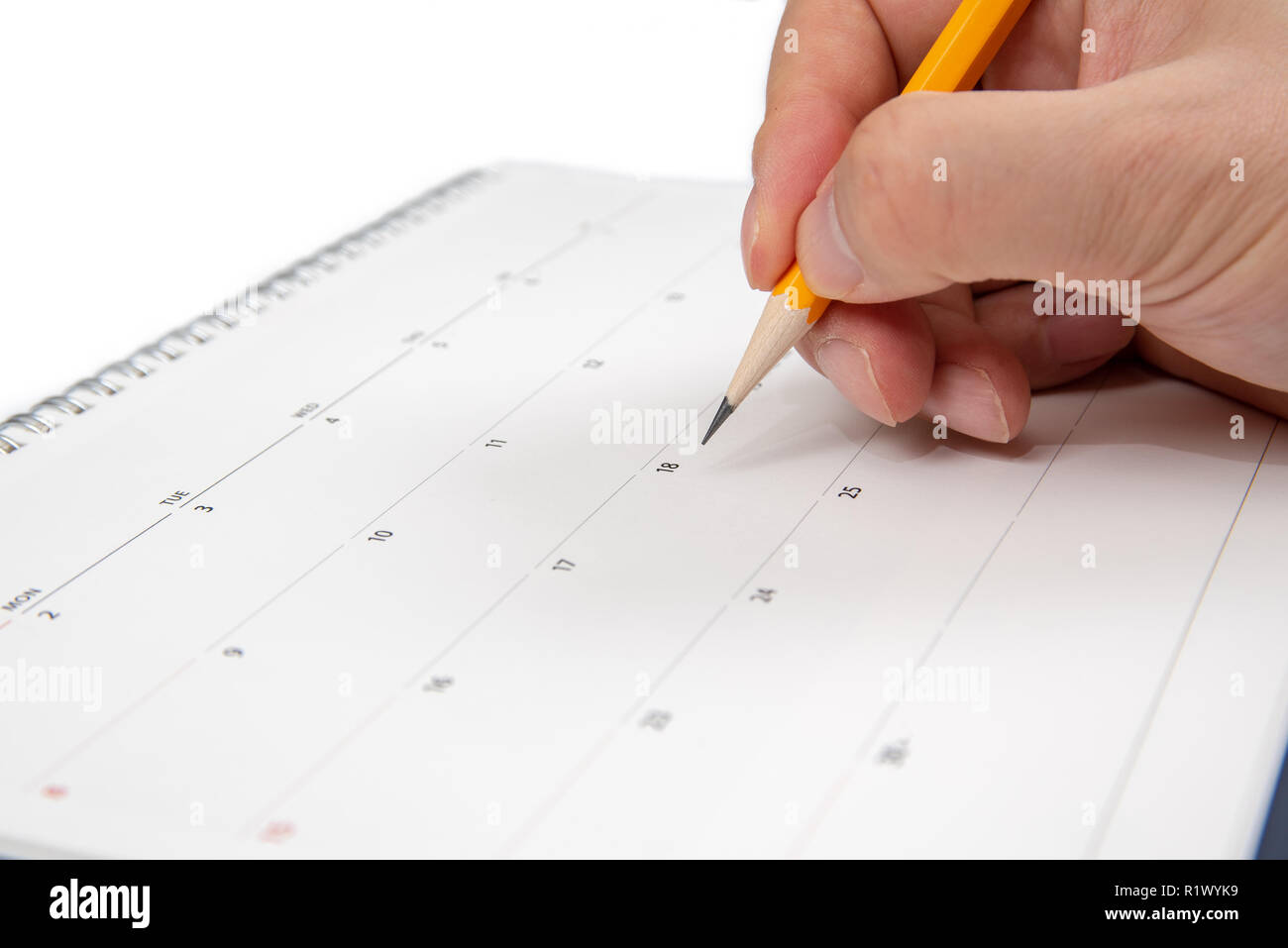 Un uomo di mano che tiene una matita in mano e la scrittura su un calendario. Foto Stock