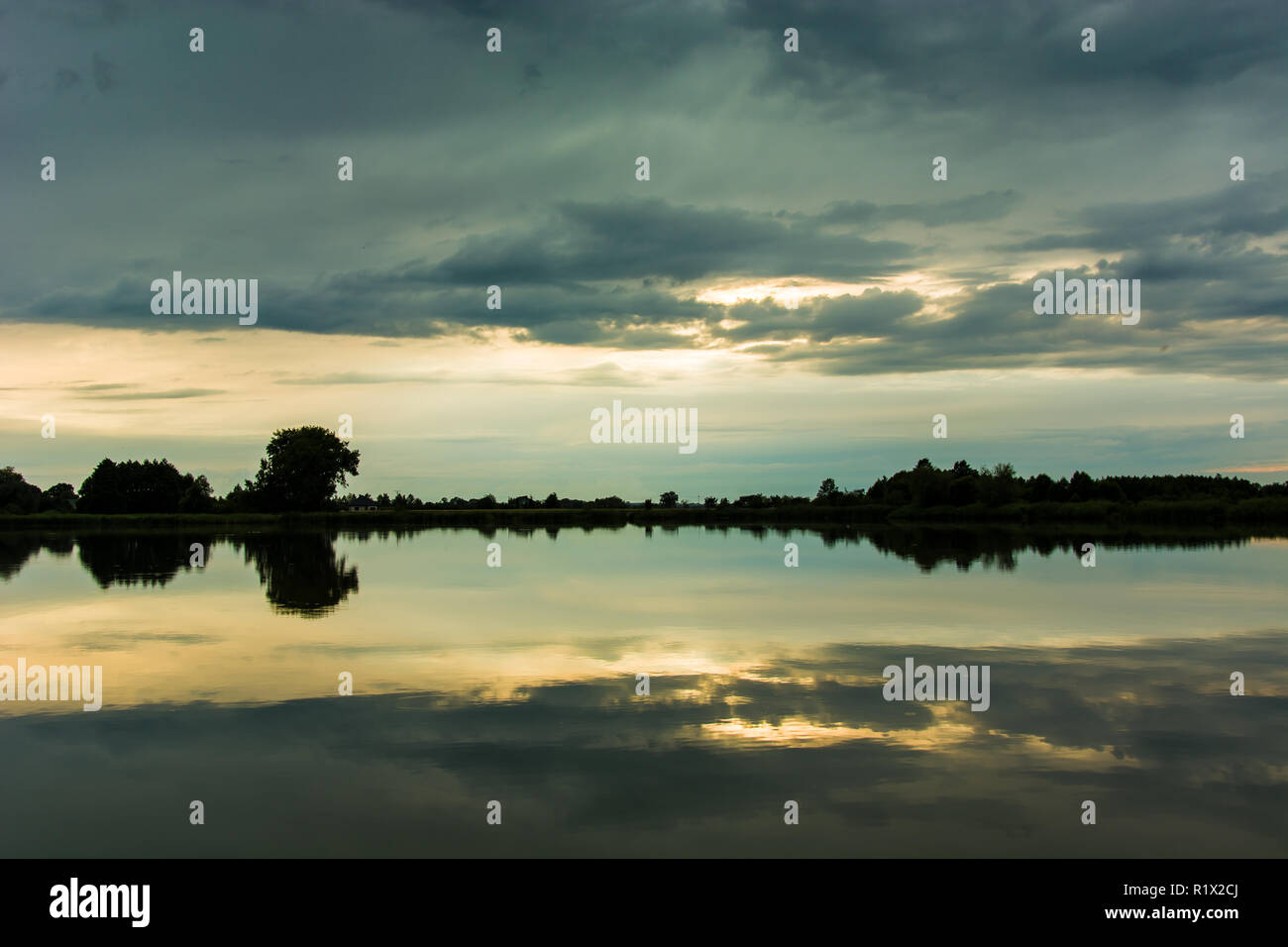 Nuvole scure nel cielo che riflette nell'acqua del lago Foto Stock
