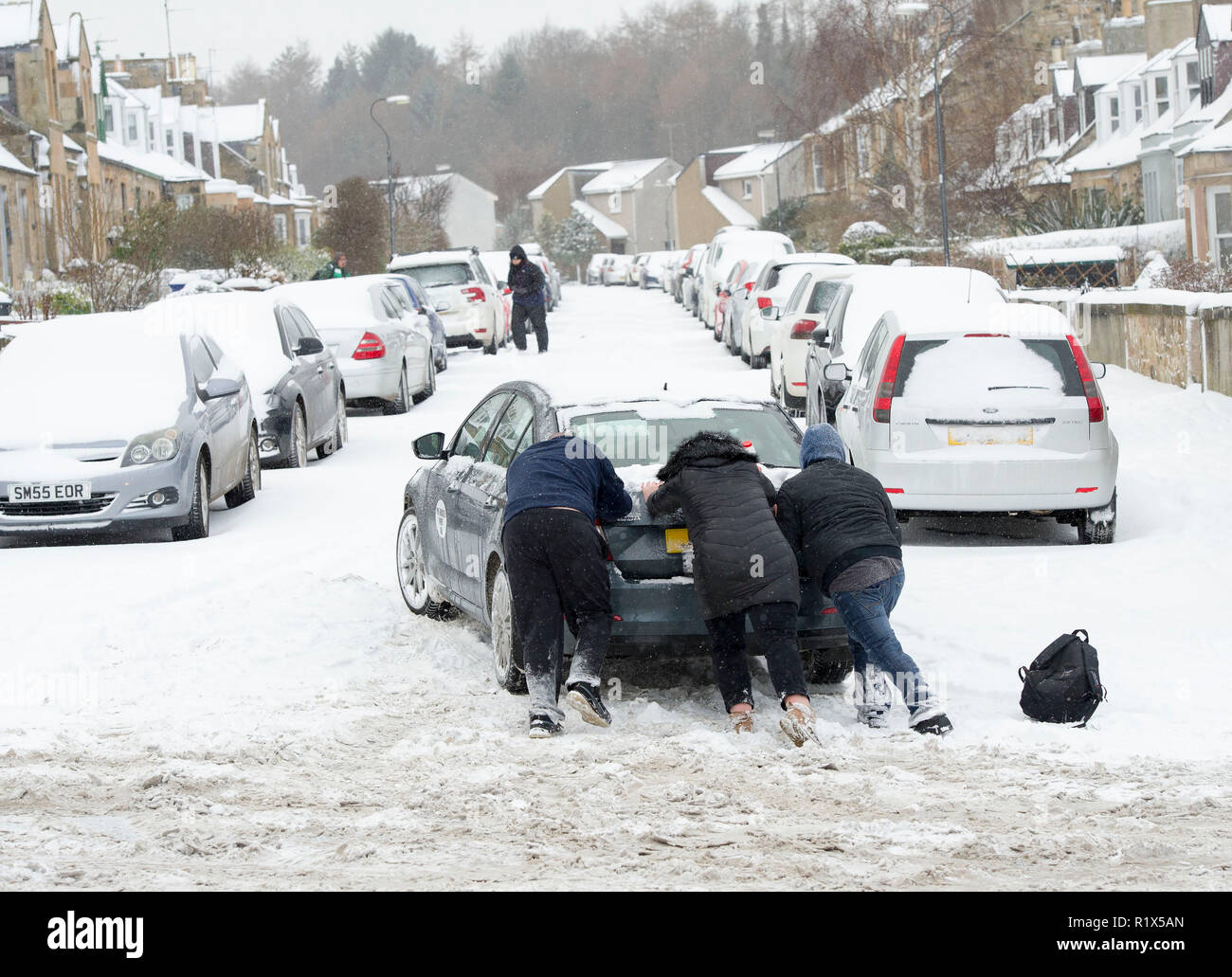 Persone aiutare a spingere un auto in Dalkieth, Scozia durante ' Bestia da est " tempesta di neve in inverno del 2018. Foto Stock