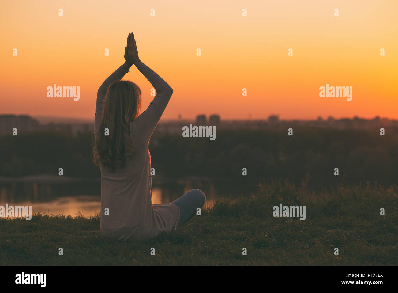 Silhouette di donna meditando al tramonto. Foto Stock