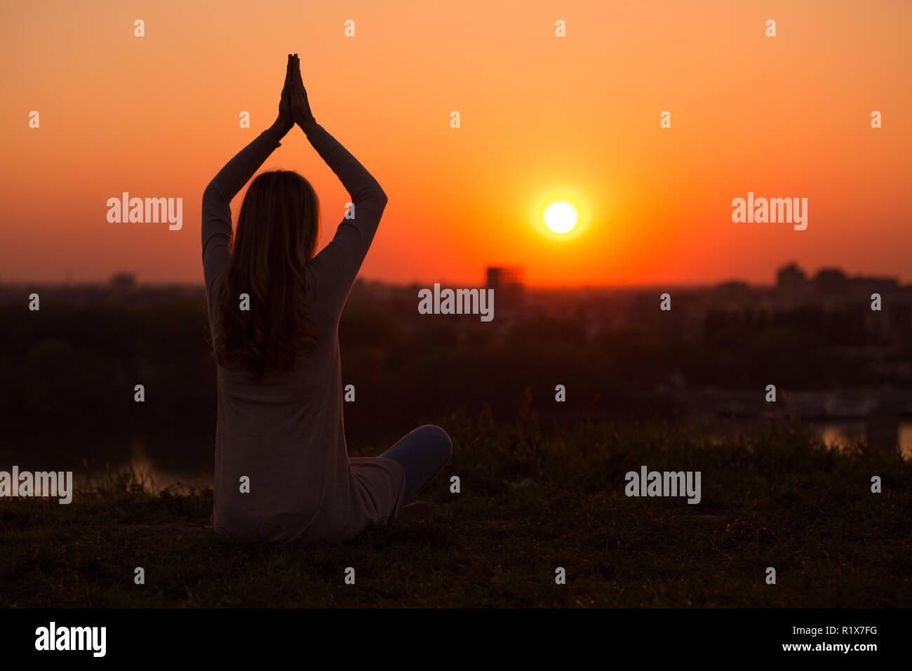 Silhouette di donna meditando al tramonto. Foto Stock