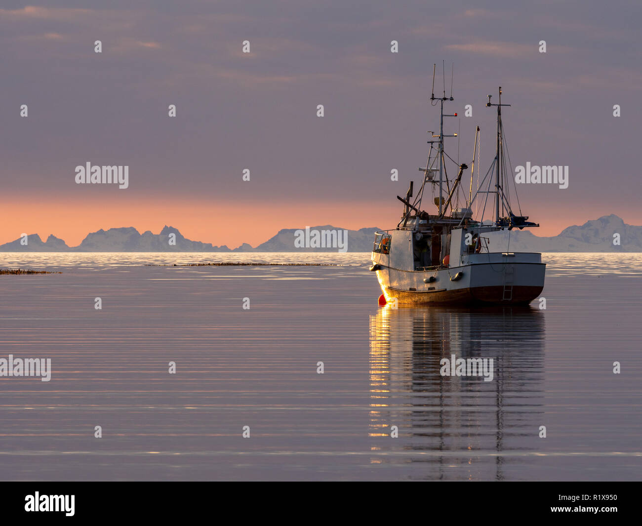 Barca da pesca girato durante il tramonto con le montagne delle Lofoten in background, girato da Mjelle fuori Bodø. Foto Stock