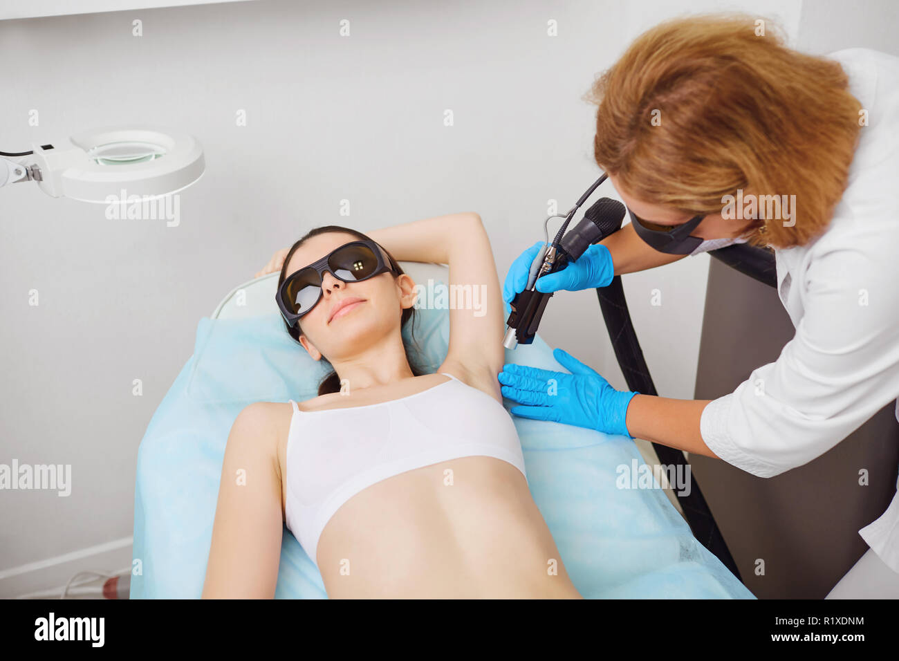 Depilazione laser sotto il braccio di una giovane donna in un cosmetolo Foto Stock