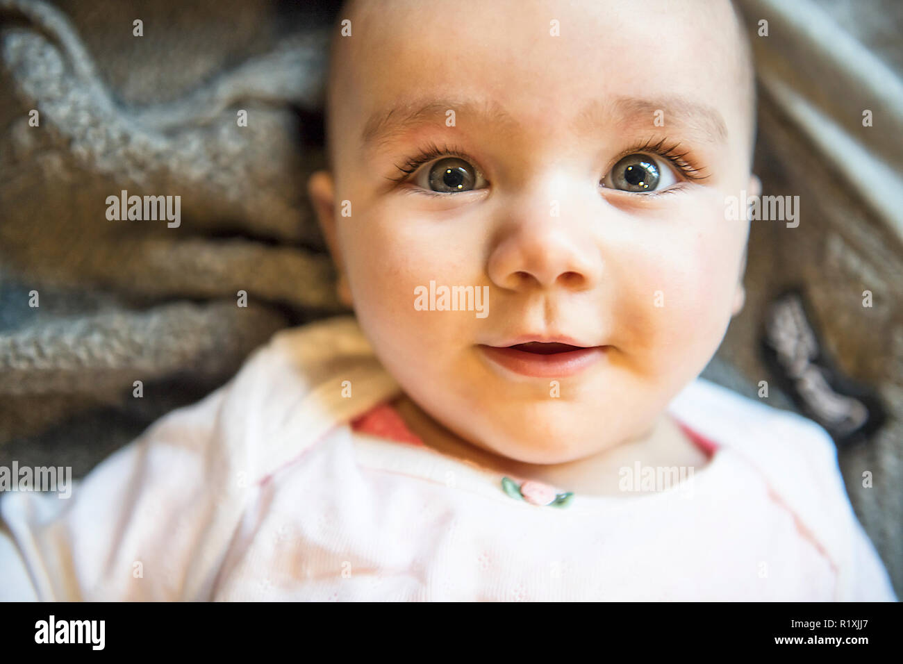 Un ritratto di un 6 mese simpatico baby girl sdraiato Foto Stock