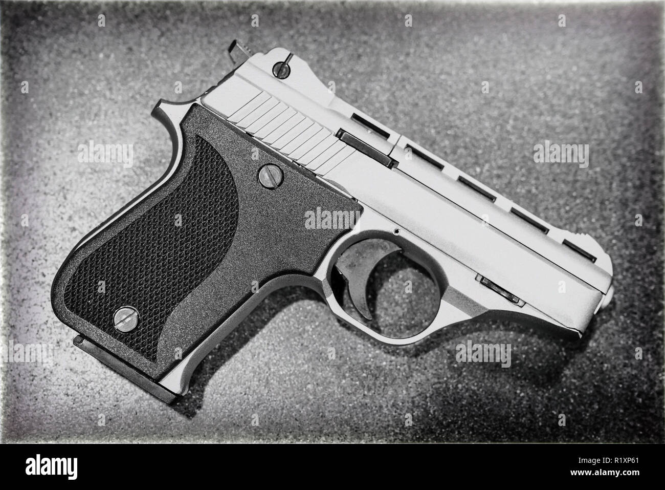 Pistola di piccole dimensioni isolata sul tavolo scuro (bianco e nero) Foto Stock