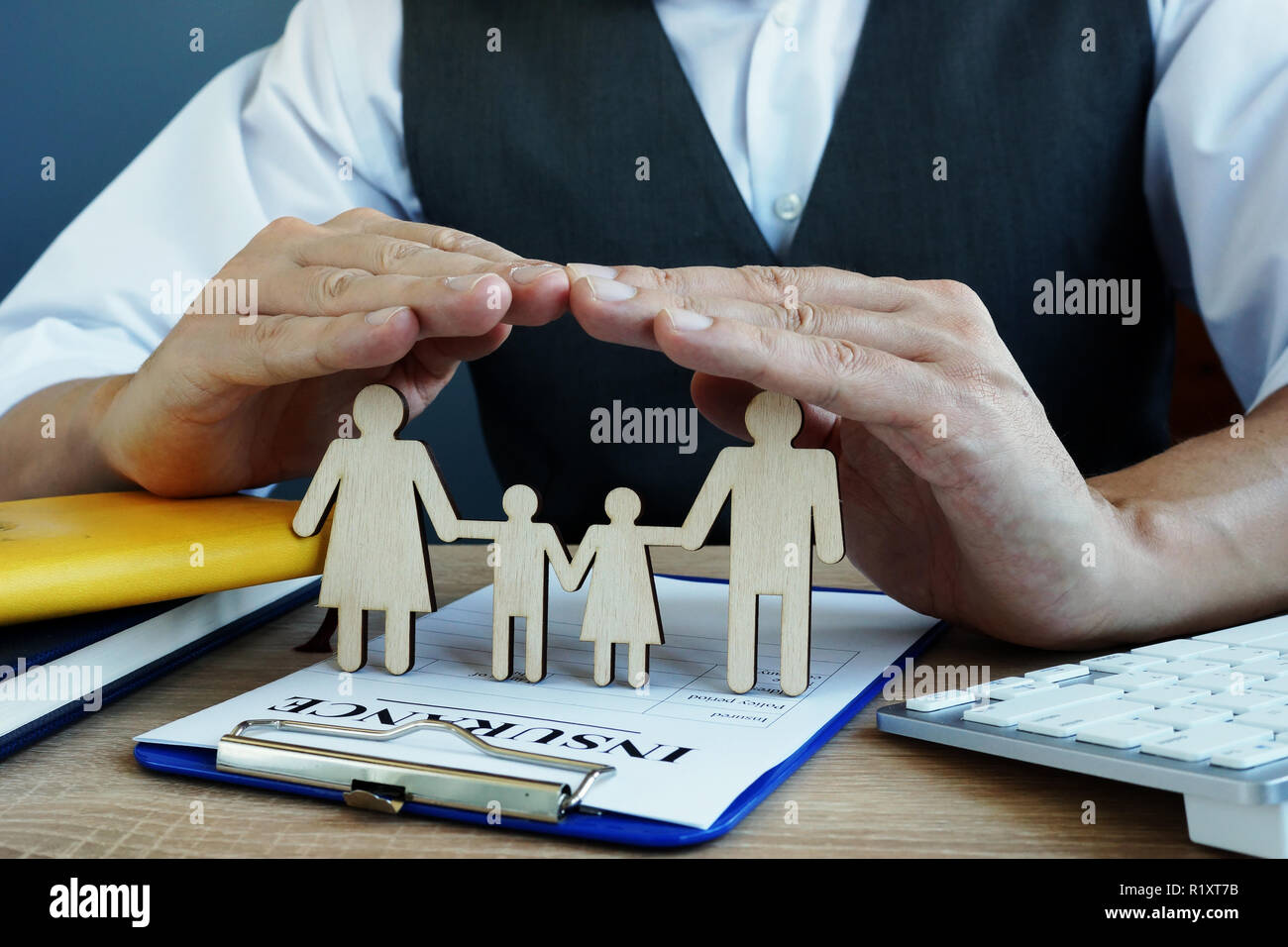 Agente famiglia protegge le figure. Polizza di assicurazione vita su una scrivania. Foto Stock