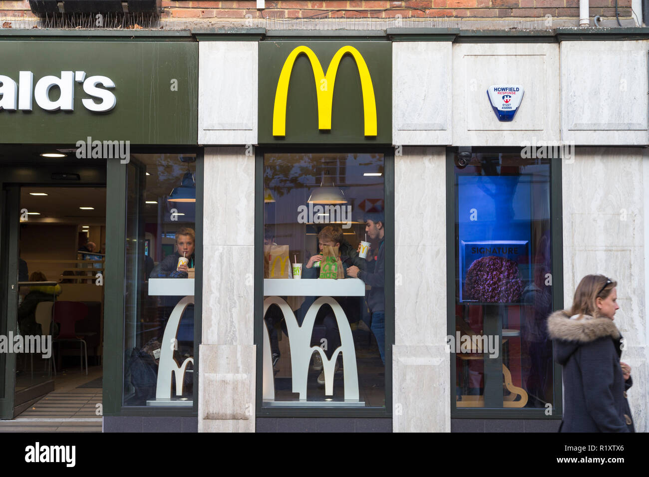 I giovani seduti in una finestra di un mcdonalds a mangiare cibo, ashford, kent, Regno Unito Foto Stock