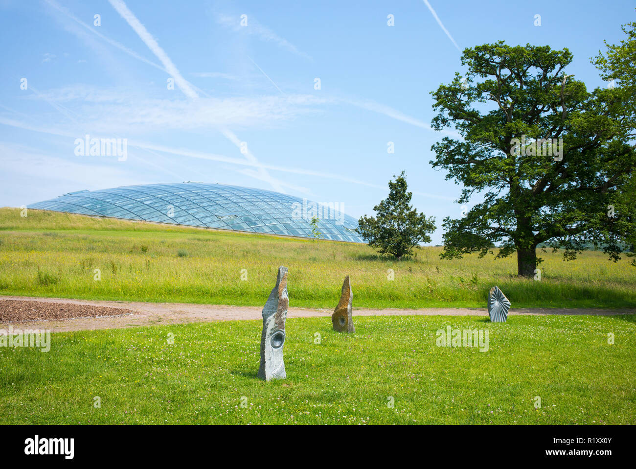Cupola a forma di tetto di vetro della grande Serra del National Botanic Garden of Wales e sculture in pietra. Foto Stock