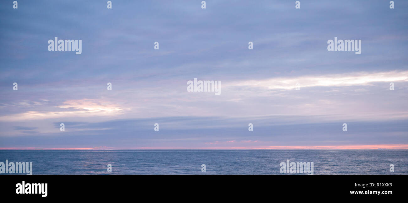 Mozzafiato, spettacolari colori pastello del tramonto sopra il mare calmo dell'Oceano Atlantico in Galles Foto Stock