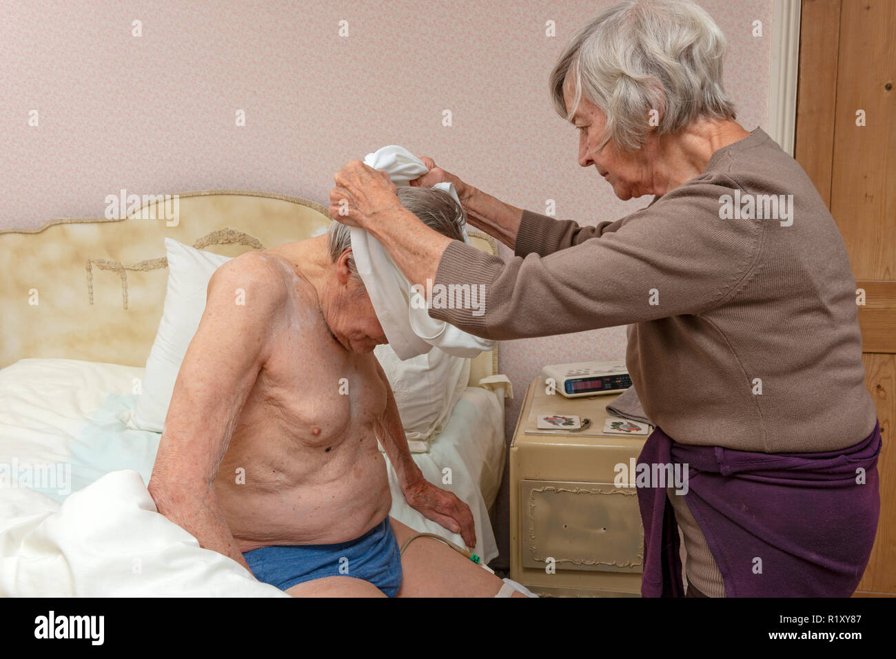 Suor aiutando il suo anziano fratello per ottenere vestito Foto Stock