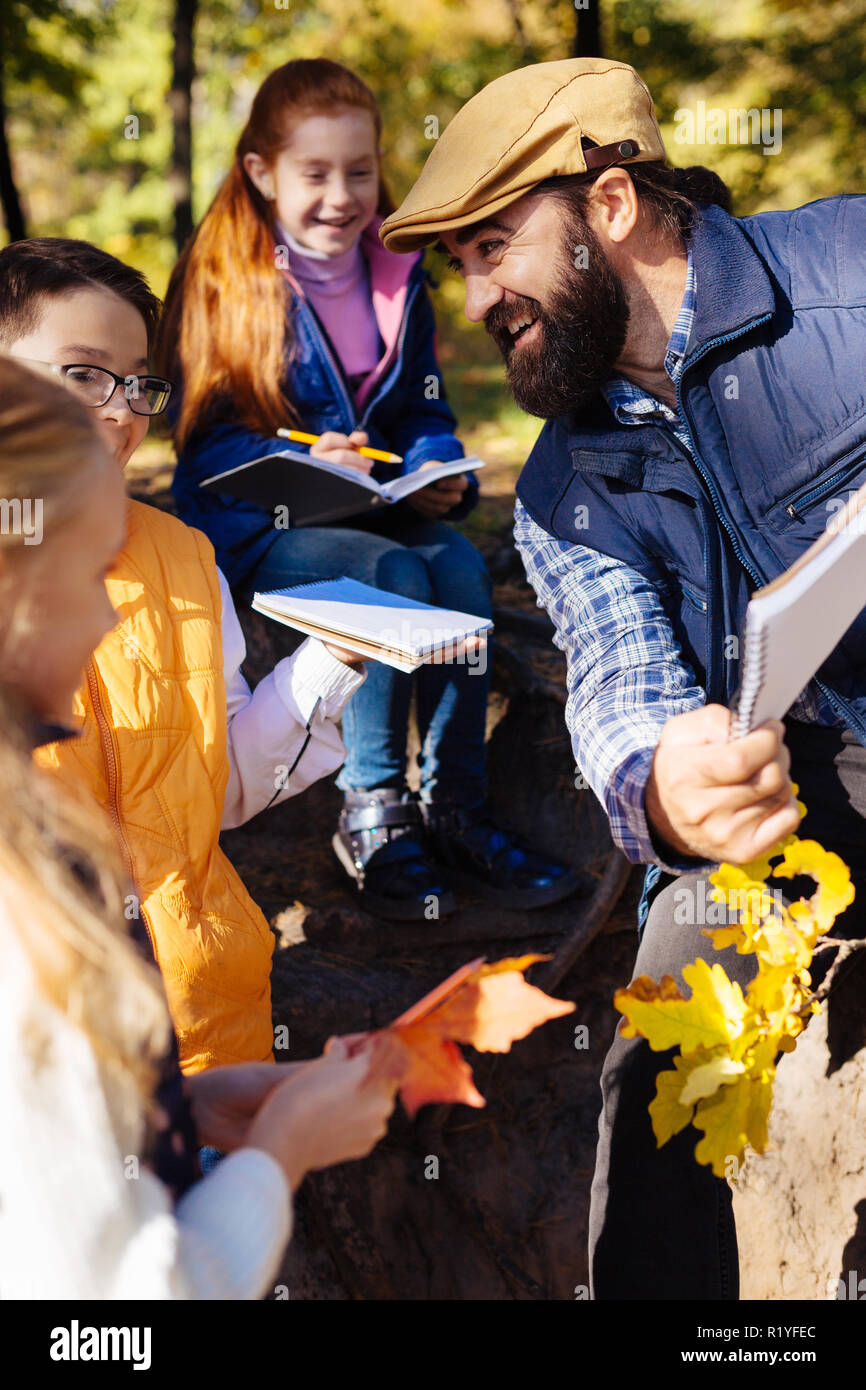 Positivo uomo barbuto a parlare con gli studenti della sua scuola Foto Stock