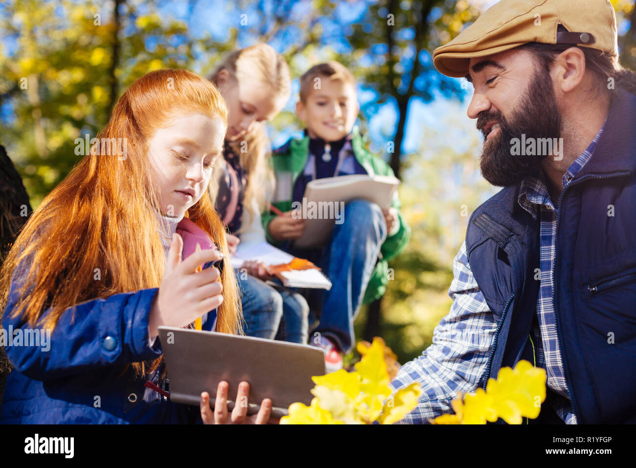 Carino dai capelli rossi ragazza cerca nel suo copybook Foto Stock