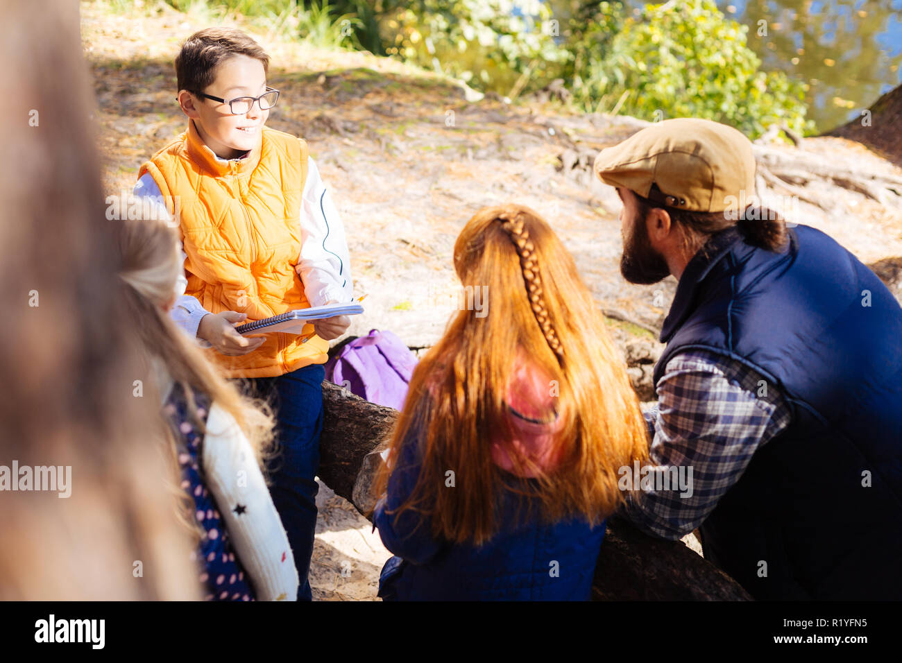 Gioiosa bel ragazzo in piedi di fronte a i suoi compagni di classe Foto Stock